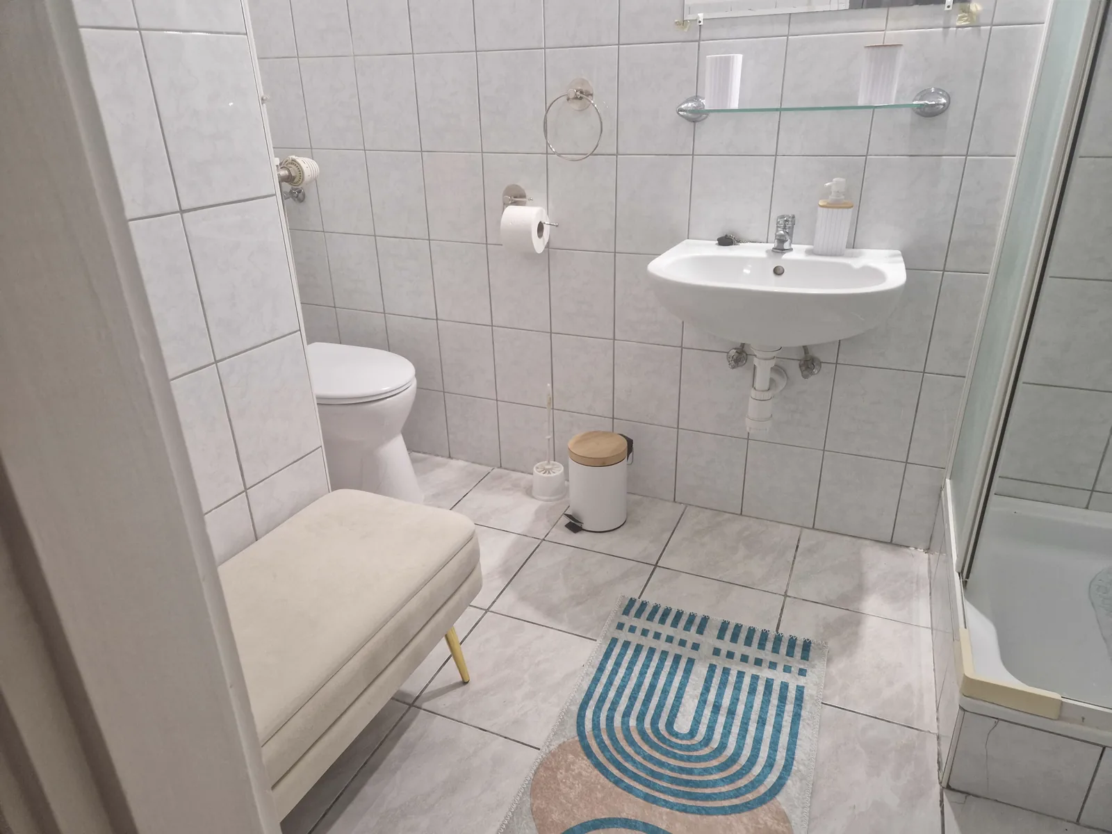 Fürdőszoba – zuhanyzó, mosdó és WC világos csempével